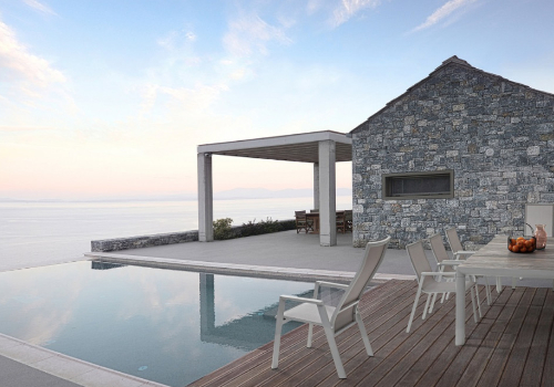 piscine d'extérieur enterré et maison en pierre avec pergola et salon de jardin