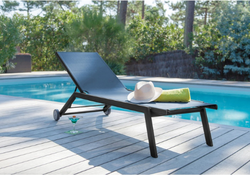 Bain de soleil sur une terrasse en bois, en bord de piscine avec cocktail pour un maximum de relaxation