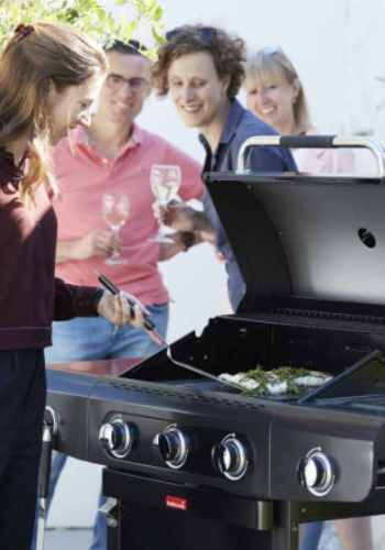 Barbecue à gaz avec brûleur sur une terrasse en famille.