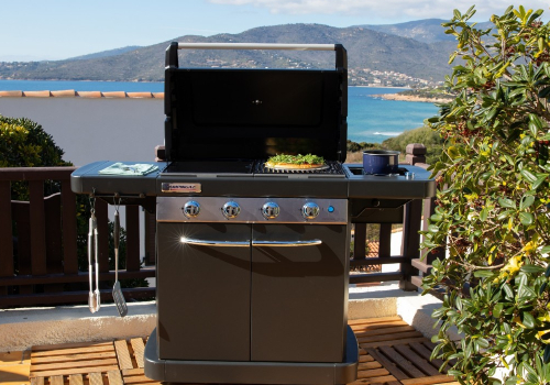 Barbecue à gaz campingaz avec ses 2 déssertessur terrasse en bois face à la mer