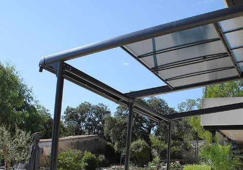 Tonnelle pergola en aluminium avec panneaux rétractables, la structure est adossée à la maison