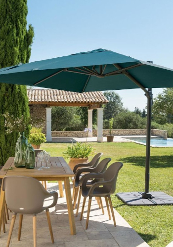 Parasol déporté dans un jardin qui apporte de l'ombre à un salon d'extérieur sur une terrasse