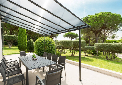 pergola adossée en aluminium et polycarbonate avec un salon de jardin dessous, sur une terrasse