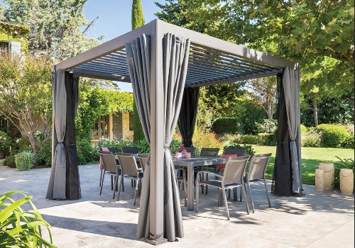 Pergola autoportante en aluminium graphite avec rideaux sur une terrasse avec un salon de jardin 10 personnes dessous.