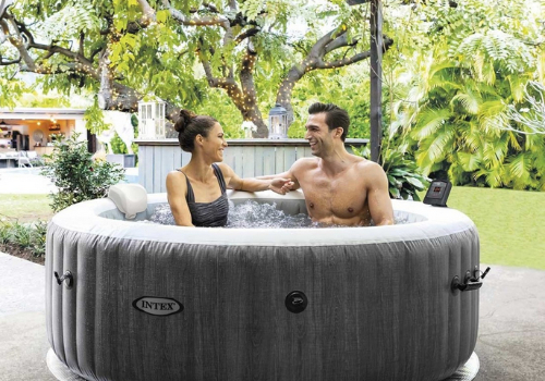 Homme et femme dans un spa gonflable rond sur une terrasse 