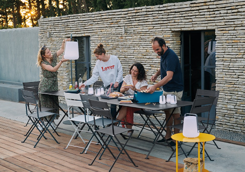 Salon de jardin en aluminium avec lampe d'extérieur, des amis partagent un repas